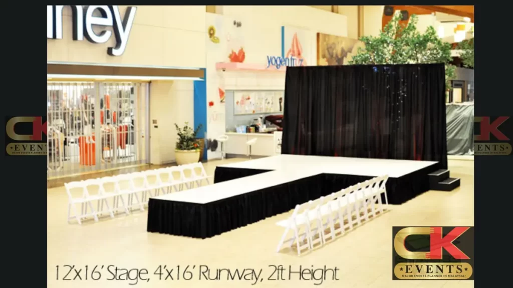 Modular black stage platform with pipe-and-drape railing for indoor ceremonies
