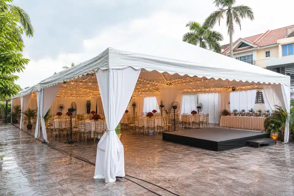 Classic white wedding marquee sample in a Malaysia house compound with banquet tables, stage and warm lights