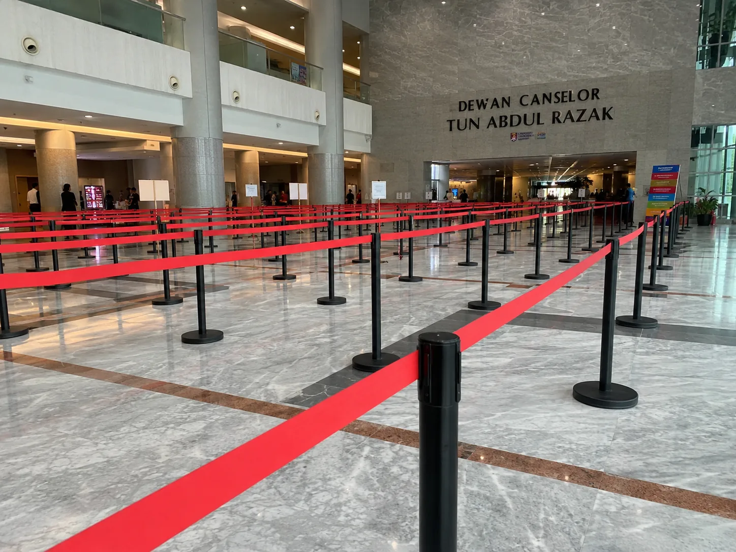 Black Q pole with red belt large queue deployment inside Malaysian university hall lobby
